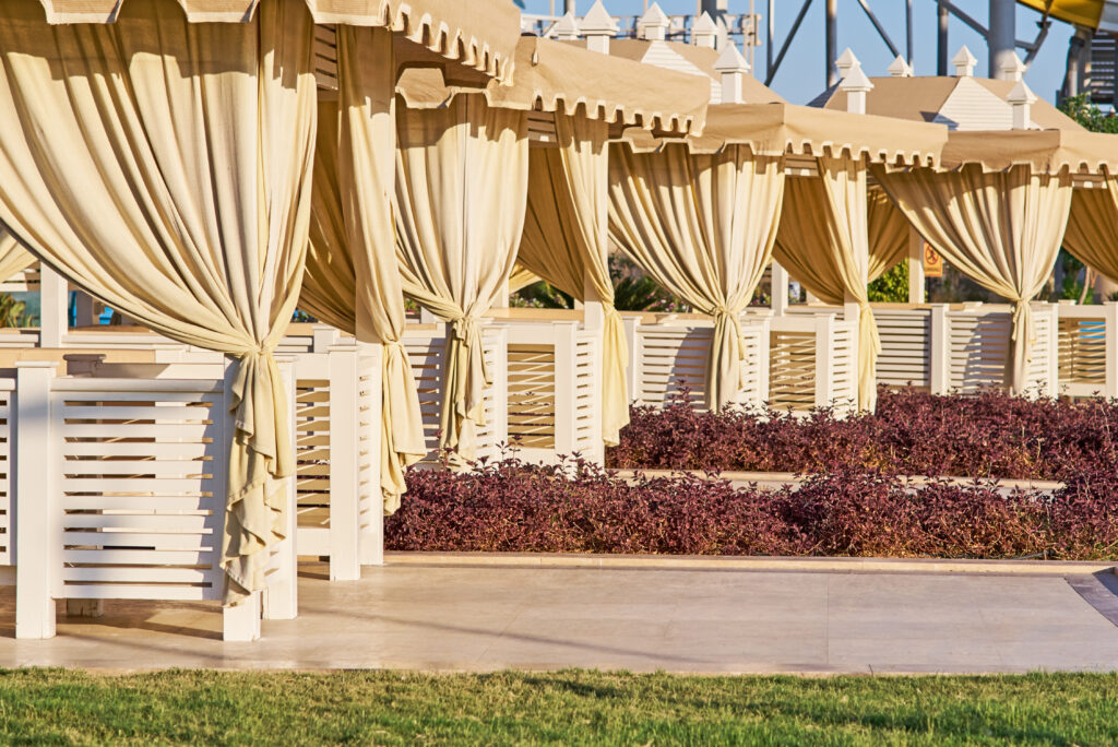 Luxueuze privébungalows met gordijnen voor privacy, ideaal voor halal vakanties, gelegen naast een zwembad met serene ambiance.