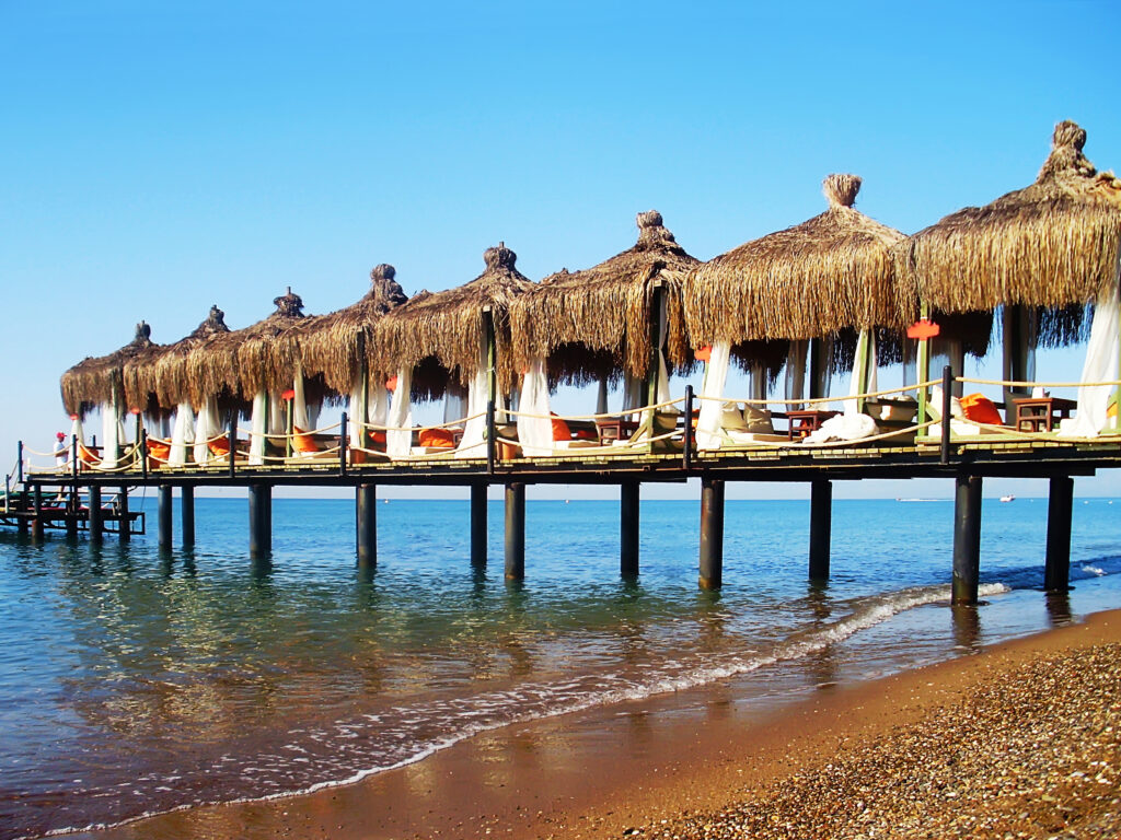 Loungezone aan zee met rieten daken, perfect voor een halal vakantie in Turkije.