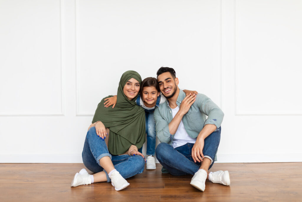 Lachend moslimgezin op vakantie samen zittend op de vloer – ideaal voor halal hotels voor gezinnen