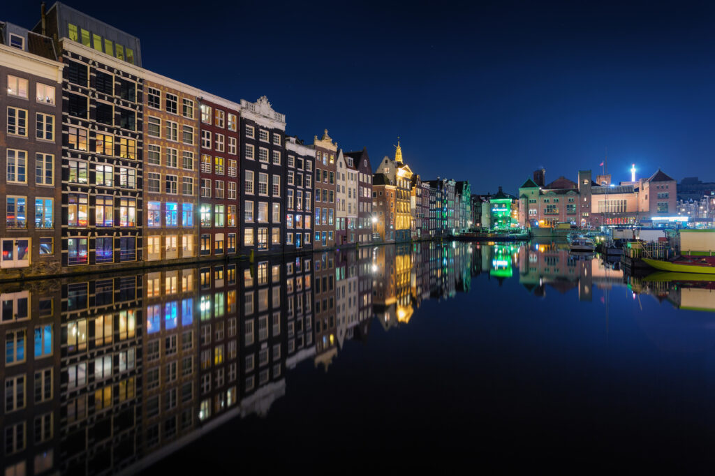 Avondzicht op Amsterdamse grachtenpanden met weerspiegeling in het water – context bij halal restaurants Nederland.