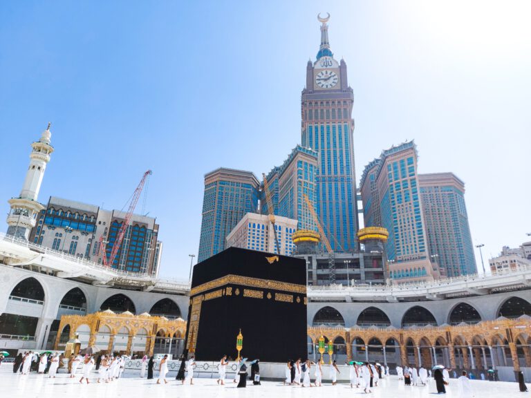Pelgrims rond de Kaaba met uitzicht op de Abraj Al-Bait torens in Mekka – symbool voor Umrah hotels en accommodaties in Mekka en Medina.