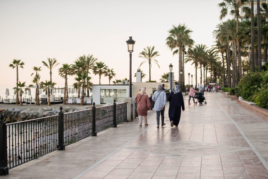 Moslimreizigers wandelen langs de boulevard van Marbella bij zonsondergang