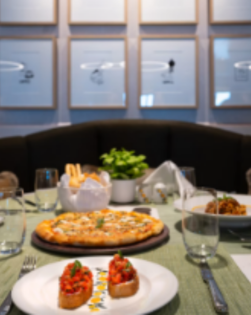 Gedekte restauranttafel met pizza, voorgerechten en glazen aan boord van AROYA