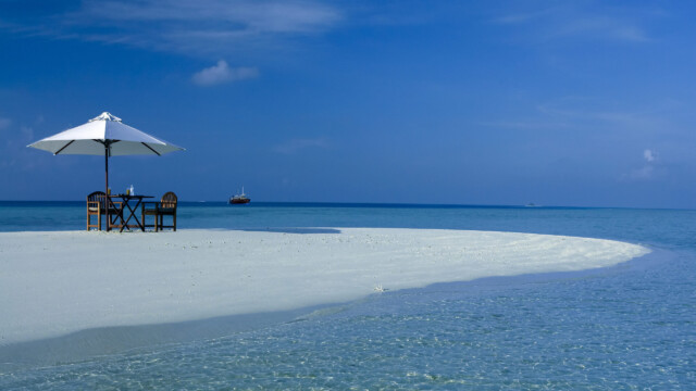 Tropisch strand met tafel en parasol, ideaal voor een luxe halalvakantie, aanbevolen door Halalvakantiegids.nl.