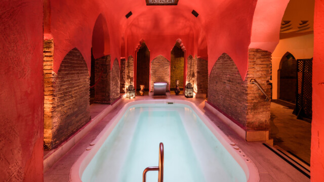 Traditionele hammam met sfeervolle rode muren en een verlicht zwembad, ideaal voor halal wellness in Turkije.