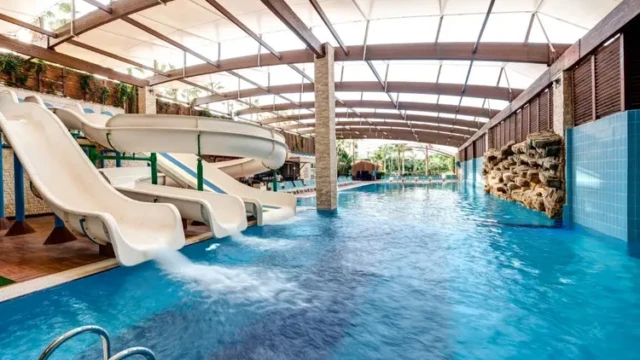 Overdekt zwembad met glijbanen voor kinderen en families. Overdekt zwembad met waterglijbanen in Adenya Hotel & Resort