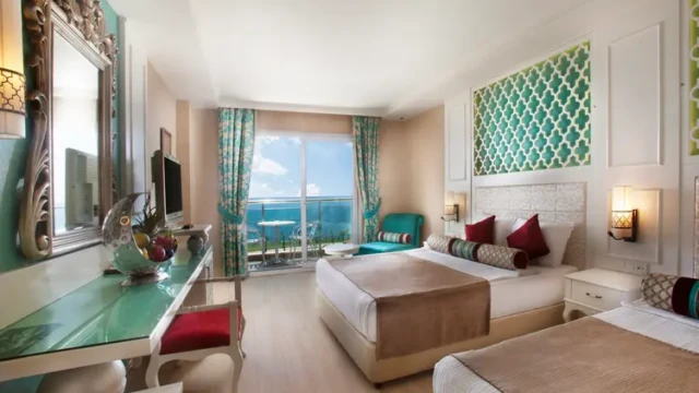 Ruime en moderne hotelkamer met balkon en panoramisch uitzicht op de Middellandse Zee. Luxe kamer met balkon en zeezicht in Adenya Hotel & Resort