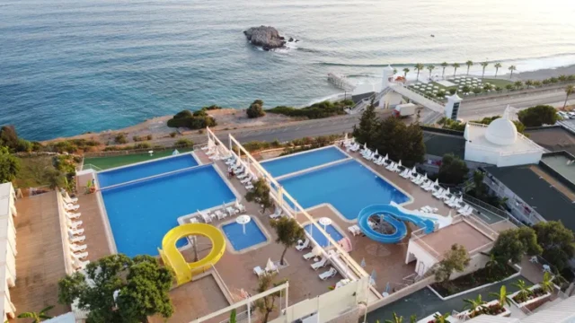Zwembadcomplex met meerdere baden en glijbanen, direct aan zee. Luchtfoto zwembaden met glijbanen en uitzicht op zee – Sea Star Hotel Alanya