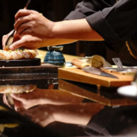 Een chef-kok bereidt een gerecht aan de counter van het Aziatische Bamboo Kitchen. Chef-kok bereidt een gerecht aan de counter van Bamboo Kitchen op AROYA