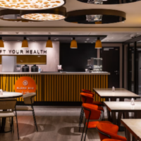 Blend heeft een eigentijdse counter en kleurrijke zitplaatsen voor een ontspannen pauze aan boord. Modern interieur van Blend met oranje stoelen, tafels en een verlichte counter