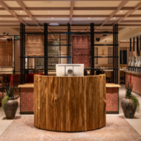 De entree van IRTH combineert warm hout met decoratieve patronen en een eigentijdse inrichting. Entree van IRTH met houten ontvangstbalie en decoratieve Arabische patronen