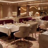 Khuzama Restaurant biedt een luxe eetomgeving met warme verlichting en stijlvol gedekte tafels. Luxe interieur van Khuzama Restaurant met gedekte tafels en bordeauxrode banken