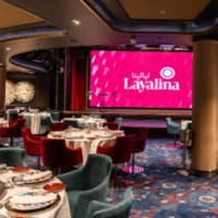 Layalina combineert een sfeervolle restaurantruimte met een podium voor entertainment aan boord. Interieur van Layalina Restaurant met gedekte tafels, kleurrijke stoelen en een podium