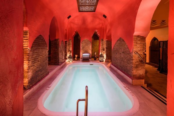 Traditionele hammam met sfeervolle rode muren en een verlicht zwembad, ideaal voor halal wellness in Turkije.